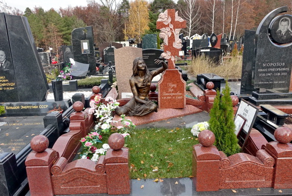 Статуя сидящей женщины слева от православного креста на подставке